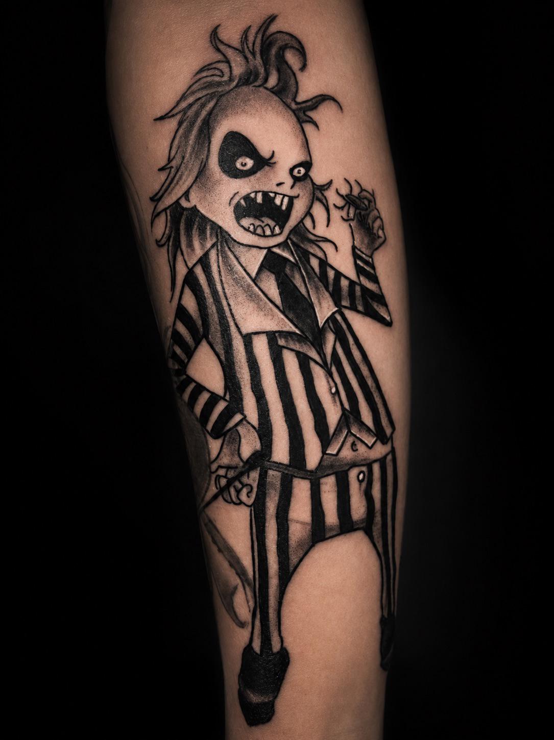 Black-&-Grey-Tattoo einer gestreiften Comicfigur am Unterarm