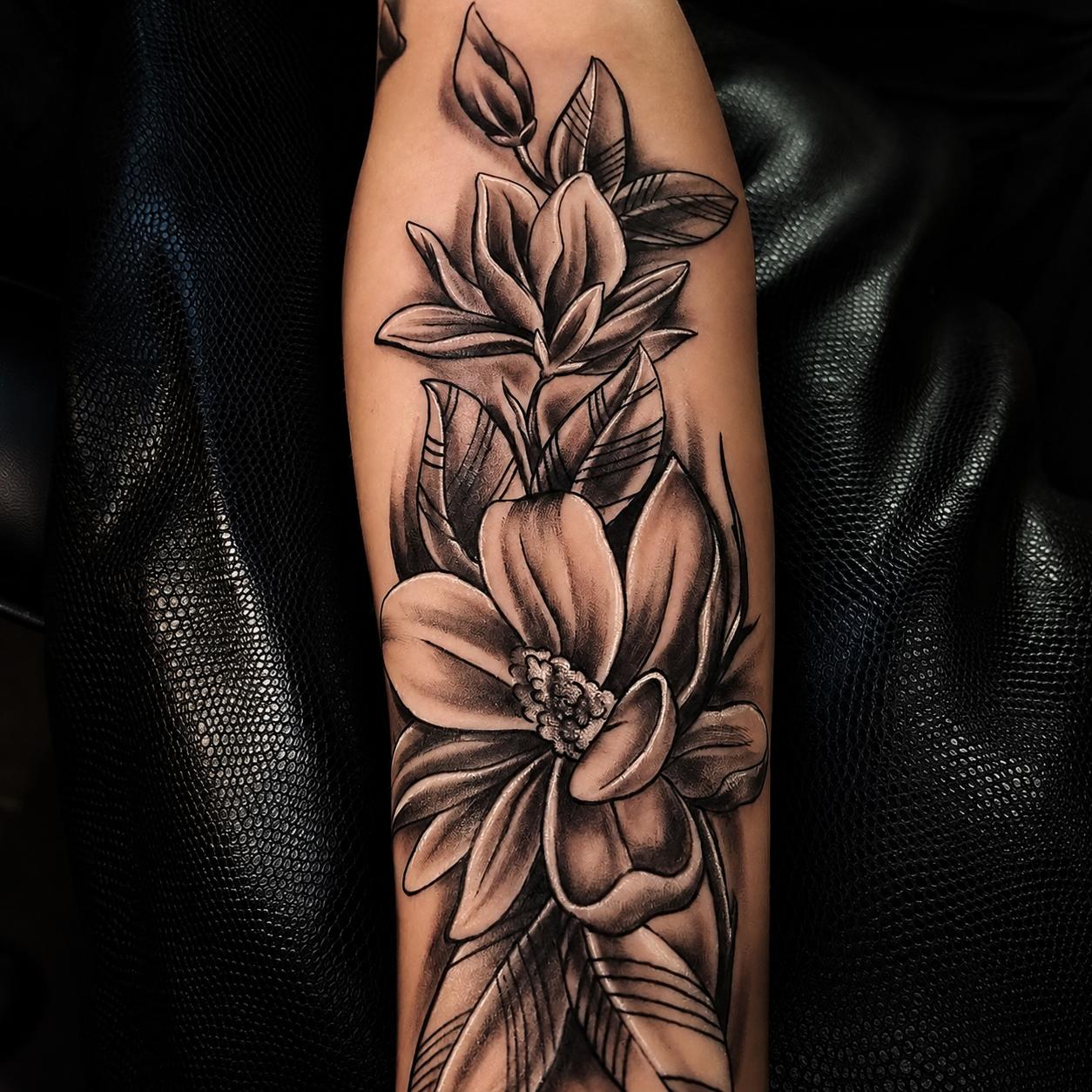 Black-&-Grey-Tattoo einer Magnolienblüte am Unterarm