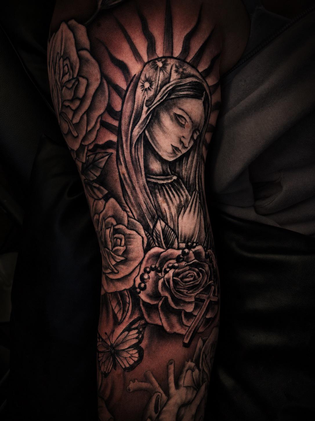 Black-&-Grey-Tattoo einer betenden Madonna mit Rosen auf dem Oberarm