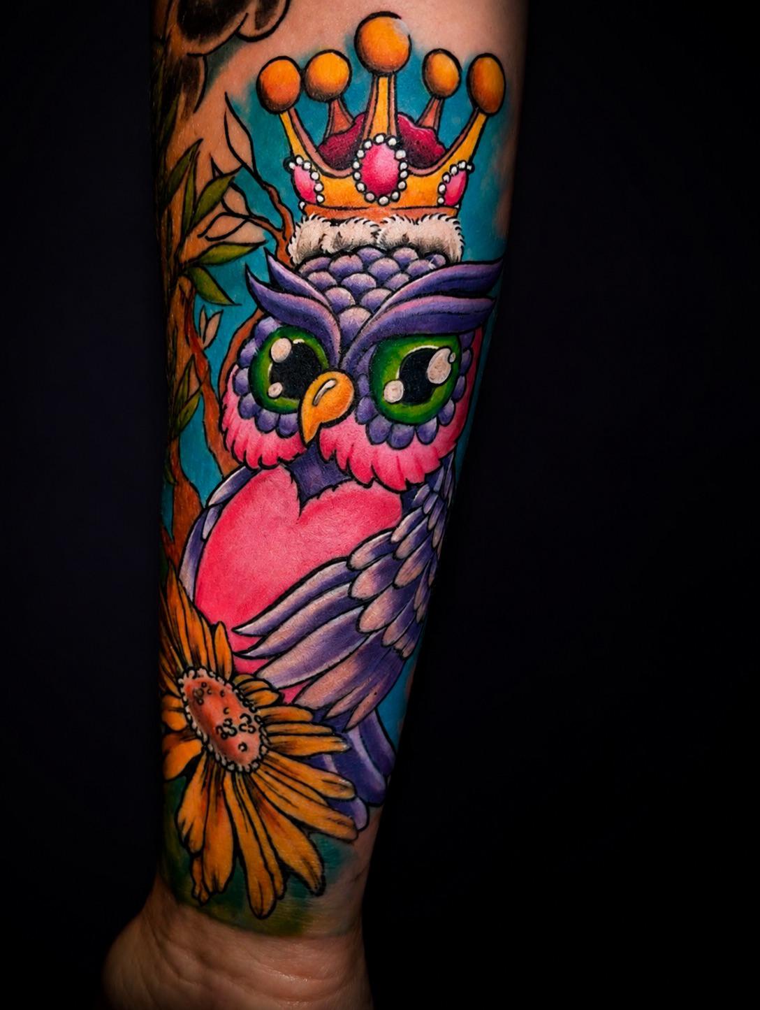 Farbiges Tattoo einer Eule mit Krone und Sonnenblume am Unterarm